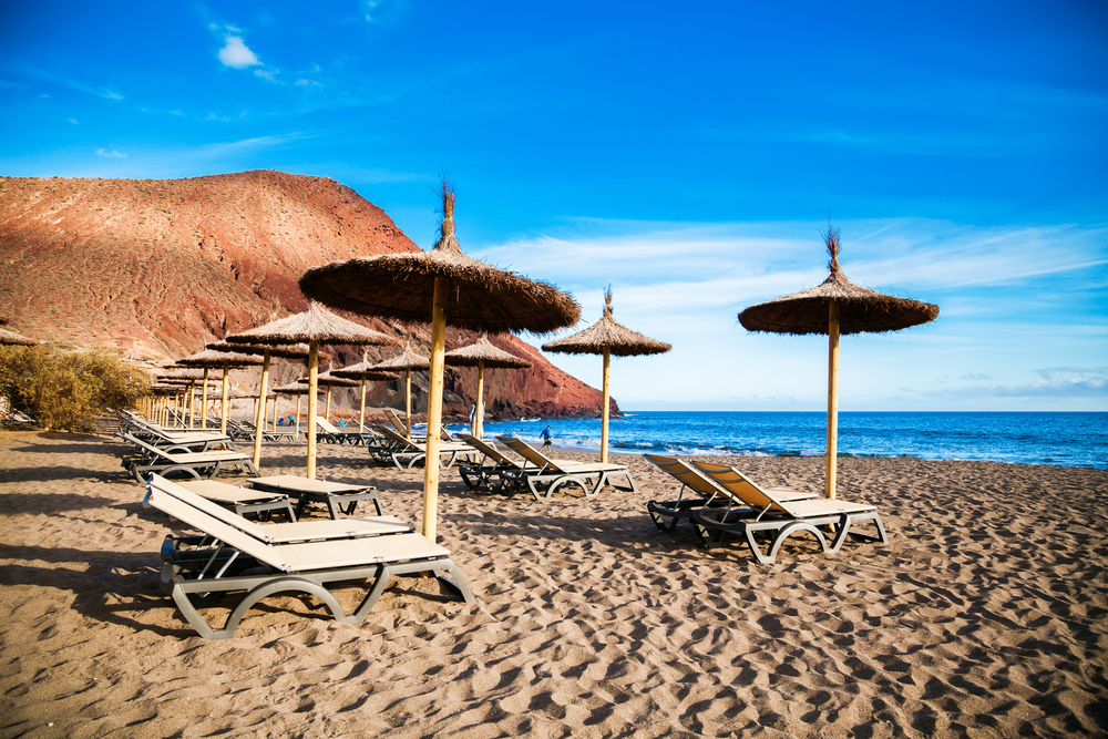 The equipped with chaise-longues and sun umbrellas beach Playa de la Tejita, Tenerife, Canary Islands